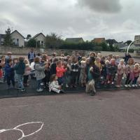 Temps d'échange et de chant avec le Père Florent dans la cour de l'école